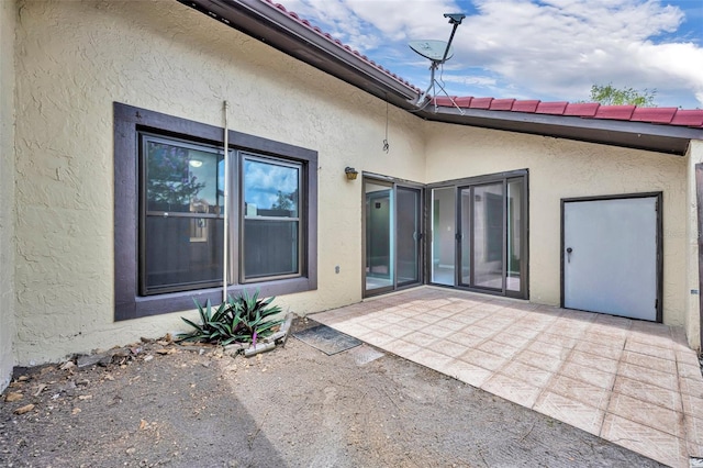 557 Hunter Cir, Kissimmee, FL 34758 - view of exterior entry with stucco siding and a patio