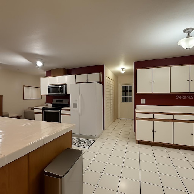 831 Fletcher Rd SE, Palm Bay, FL 32909 - kitchen with appliances with stainless steel finishes, tile counters, white cabinets, and light tile patterned floors