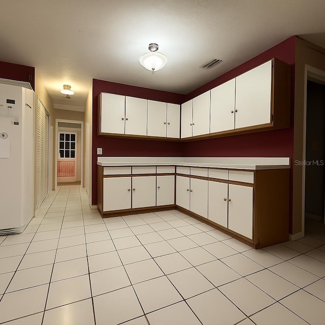 831 Fletcher Rd SE, Palm Bay, FL 32909 - kitchen with white refrigerator, white cabinets, light countertops, and light tile patterned flooring
