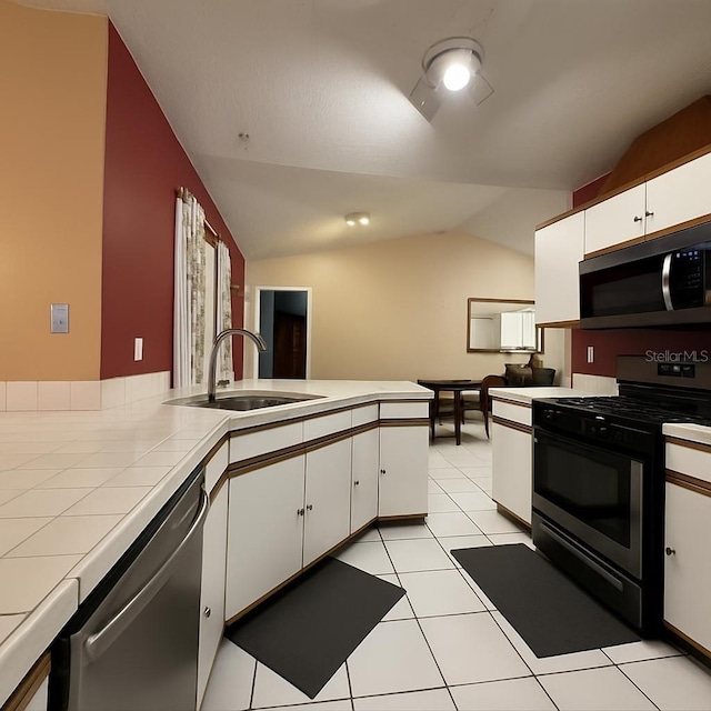 831 Fletcher Rd SE, Palm Bay, FL 32909 - kitchen featuring stainless steel appliances, tile countertops, vaulted ceiling, white cabinets, and light tile patterned floors