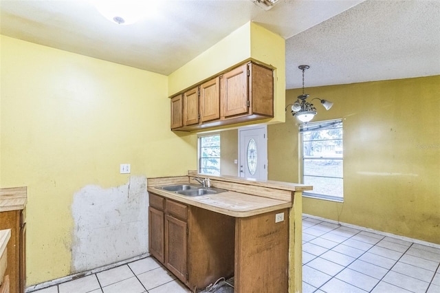 1212 N Hudson St, Orlando, FL 32808 - kitchen with a peninsula, light tile patterned flooring, brown cabinets, light countertops, and pendant lighting