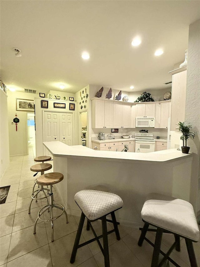 3539 Maple Ridge Loop, Kissimmee, FL 34741 - kitchen with white appliances, a breakfast bar, white cabinetry, a peninsula, and recessed lighting