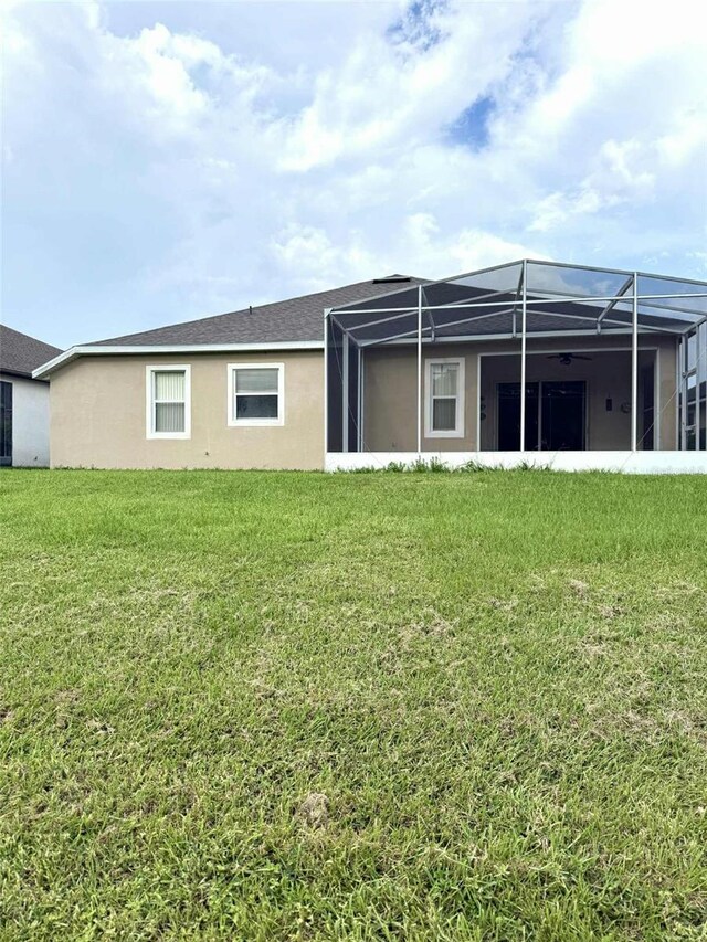 3539 Maple Ridge Loop, Kissimmee, FL 34741 - rear view of house featuring a yard, glass enclosure, and stucco siding