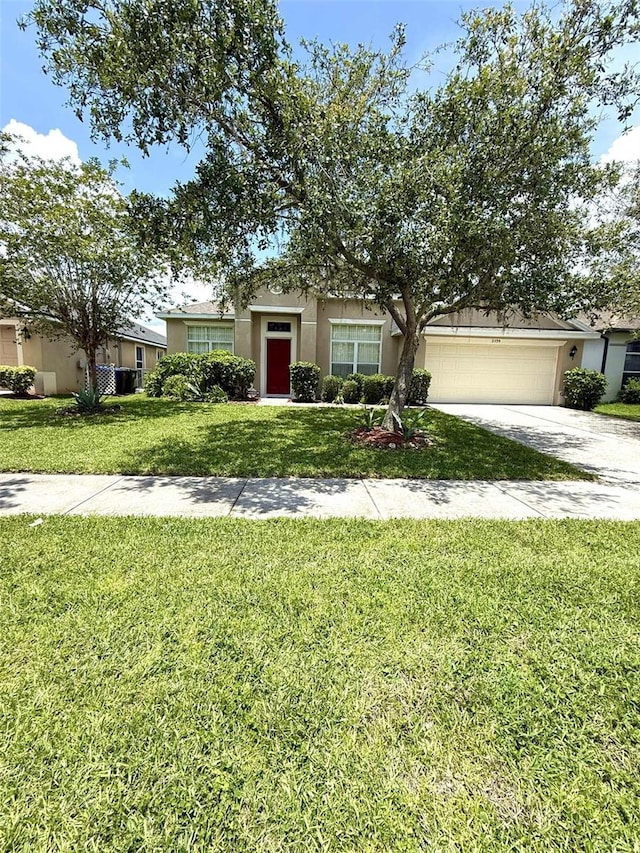 3539 Maple Ridge Loop, Kissimmee, FL 34741 - view of property hidden behind natural elements with stucco siding, a garage, a front lawn, and driveway