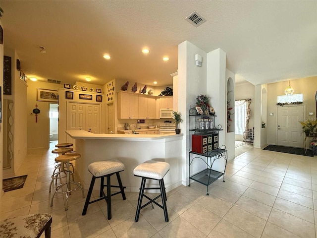 3539 Maple Ridge Loop, Kissimmee, FL 34741 - kitchen featuring light tile patterned flooring, light countertops, a peninsula, a breakfast bar, and white microwave
