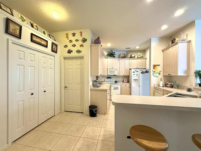 3539 Maple Ridge Loop, Kissimmee, FL 34741 - kitchen featuring white appliances, light tile patterned floors, a peninsula, light countertops, and a breakfast bar