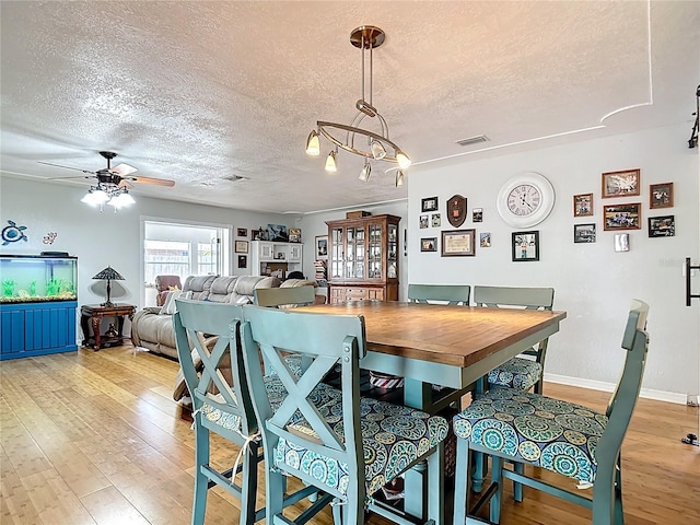 1475 Mars St, Merritt Island, FL 32953 - dining area with a textured ceiling, light wood finished floors, ceiling fan, and a chandelier