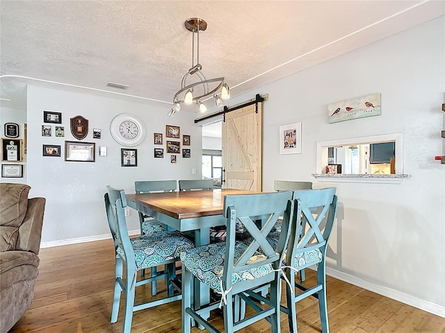 1475 Mars St, Merritt Island, FL 32953 - dining room with a barn door, hardwood / wood-style floors, and a textured ceiling