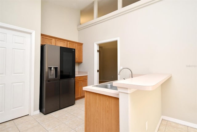2131 Kaylas Ct, Orlando, FL 32817 - kitchen with black fridge with ice dispenser, a peninsula, light tile patterned floors, a breakfast bar, and brown cabinetry