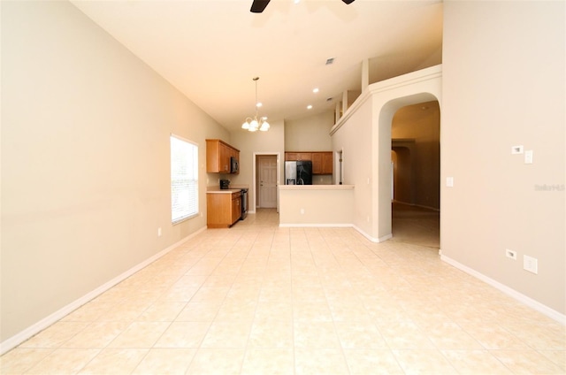 2131 Kaylas Ct, Orlando, FL 32817 - unfurnished living room with arched walkways, ceiling fan, a chandelier, light tile patterned floors, and vaulted ceiling