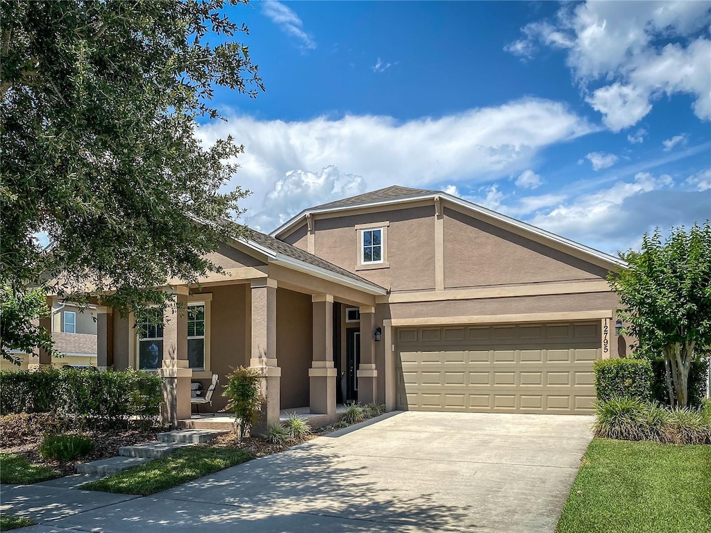 12795 Bosworth Ave, Windermere, FL 34786 - view of front of home with stucco siding, concrete driveway, a garage, and a porch