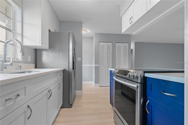 1066 Swanson Dr, Deltona, FL 32738 - kitchen with stainless steel appliances, light wood-style floors, white cabinetry, blue cabinetry, and light stone countertops