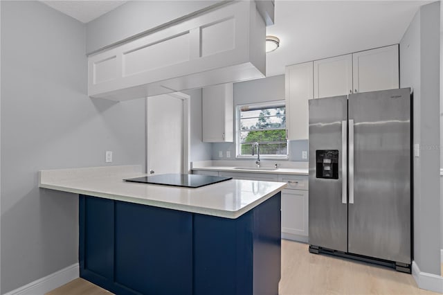 1066 Swanson Dr, Deltona, FL 32738 - kitchen with stainless steel fridge, black electric stovetop, a peninsula, light wood finished floors, and white cabinets