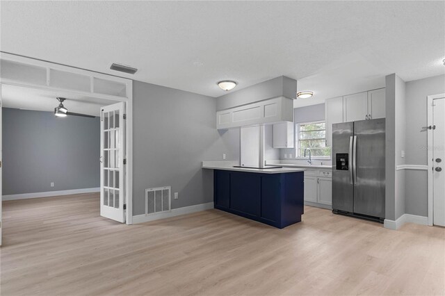 1066 Swanson Dr, Deltona, FL 32738 - kitchen with stainless steel refrigerator with ice dispenser, light wood-type flooring, light countertops, and white cabinetry