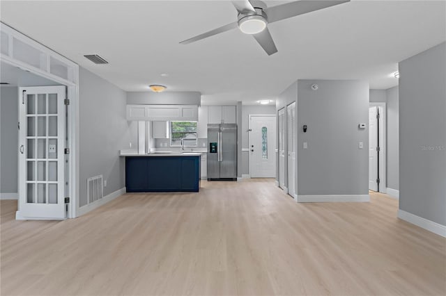 1066 Swanson Dr, Deltona, FL 32738 - kitchen with stainless steel fridge, a peninsula, light wood-type flooring, ceiling fan, and light countertops