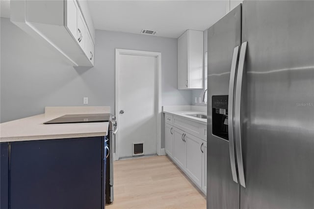 1066 Swanson Dr, Deltona, FL 32738 - kitchen with appliances with stainless steel finishes, light wood-style flooring, light countertops, white cabinetry, and blue cabinets