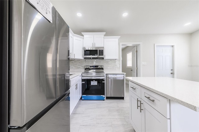 226 Palmyra Dr, Orlando, FL 32807 - kitchen featuring appliances with stainless steel finishes, tasteful backsplash, white cabinetry, light marble finish floors, and recessed lighting