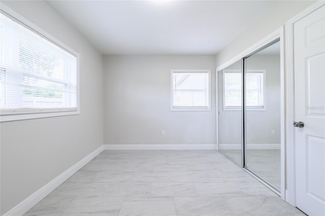 226 Palmyra Dr, Orlando, FL 32807 - unfurnished bedroom featuring light marble finish floors, multiple windows, and a closet