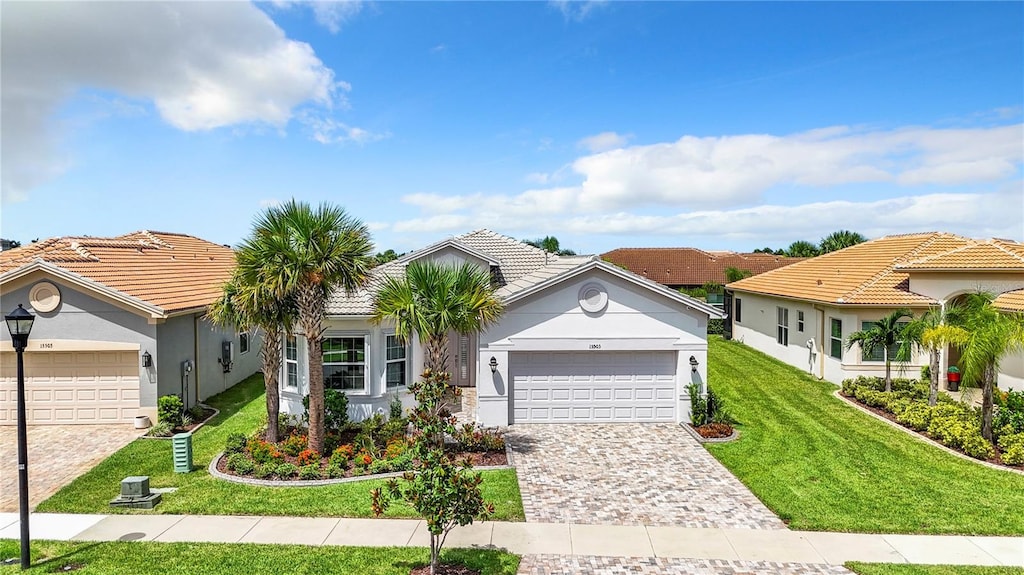 15503 Corona Del Mar Dr, Wimauma, FL 33598 - mediterranean / spanish-style home with a garage, a front yard, decorative driveway, stucco siding, and a tile roof