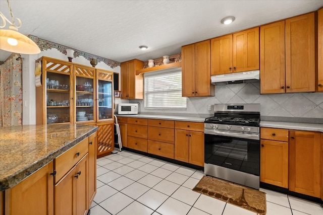 5324 Barefoot Path, Kissimmee, FL 34746 - kitchen featuring gas range, under cabinet range hood, tasteful backsplash, white microwave, and brown cabinets
