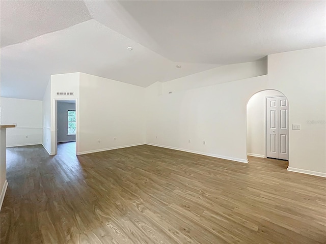 2353 Kingscrest Cir, Apopka, FL 32712 - empty room featuring lofted ceiling, wood finished floors, arched walkways, and a textured ceiling