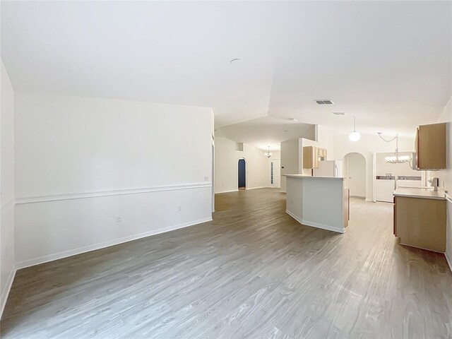 2353 Kingscrest Cir, Apopka, FL 32712 - unfurnished living room featuring arched walkways, light wood finished floors, lofted ceiling, and a chandelier