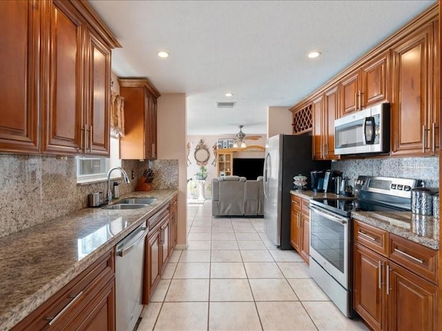 961 SW 98th Ave, Pembroke Pines, FL 33025 - kitchen featuring appliances with stainless steel finishes, a ceiling fan, brown cabinetry, light tile patterned floors, and backsplash