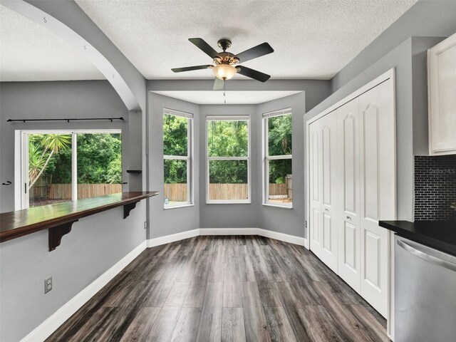 1712 Riveredge Rd, Oviedo, FL 32766 - unfurnished dining area featuring dark wood finished floors, a textured ceiling, ceiling fan, and arched walkways
