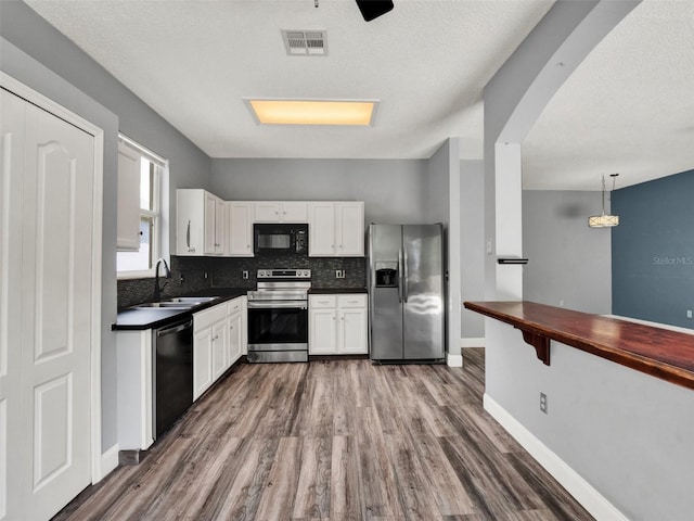 1712 Riveredge Rd, Oviedo, FL 32766 - kitchen with stainless steel appliances, wood finished floors, white cabinets, and decorative backsplash