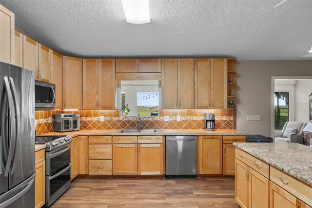 2921 Lake Tohopekaliga Blvd, Kissimmee, FL 34746 - kitchen with appliances with stainless steel finishes, a textured ceiling, light wood finished floors, tasteful backsplash, and open shelves