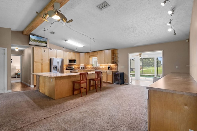 2921 Lake Tohopekaliga Blvd, Kissimmee, FL 34746 - kitchen featuring ceiling fan, stainless steel appliances, light brown cabinets, a kitchen breakfast bar, and carpet