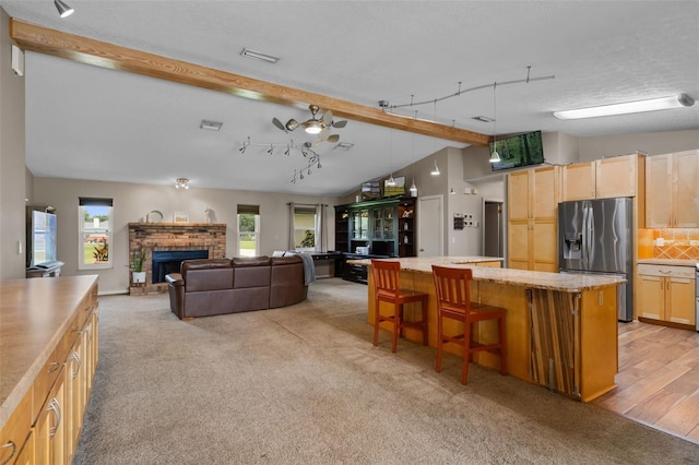 2921 Lake Tohopekaliga Blvd, Kissimmee, FL 34746 - kitchen featuring stainless steel fridge with ice dispenser, light countertops, a kitchen island, light colored carpet, and a breakfast bar