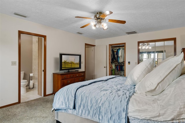 2921 Lake Tohopekaliga Blvd, Kissimmee, FL 34746 - bedroom with light colored carpet, a textured ceiling, a walk in closet, ensuite bath, and a ceiling fan