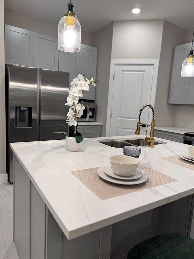 1526 Hempel Ave, Gotha, FL 34734 - kitchen with gray cabinets, light stone countertops, a kitchen island with sink, hanging light fixtures, and stainless steel refrigerator with ice dispenser