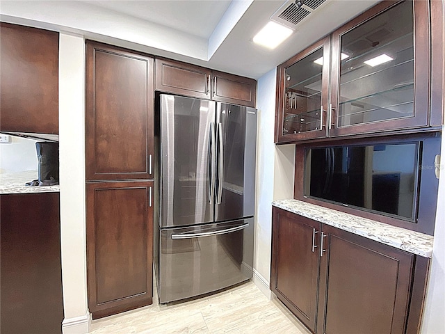 2400 Presidential Way Unit 1104, West Palm Beach, FL 33401 - kitchen with freestanding refrigerator, dark brown cabinetry, light wood-style flooring, glass insert cabinets, and light stone counters