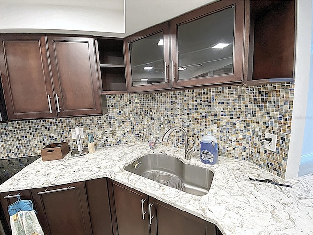 2400 Presidential Way Unit 1104, West Palm Beach, FL 33401 - kitchen featuring dark brown cabinetry, backsplash, glass insert cabinets, and light stone counters