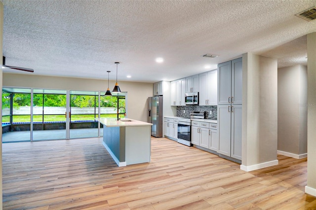 5938 Marlberry Dr, Orlando, FL 32819 - kitchen featuring appliances with stainless steel finishes, light countertops, light wood finished floors, decorative backsplash, and a textured ceiling