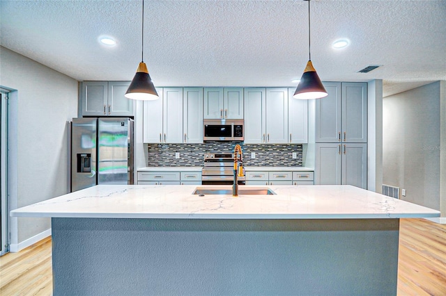 5938 Marlberry Dr, Orlando, FL 32819 - kitchen with appliances with stainless steel finishes, light wood-style flooring, decorative backsplash, light stone countertops, and a textured ceiling