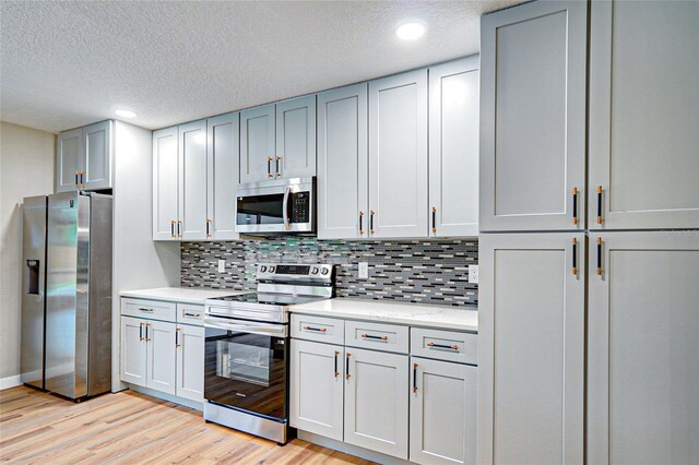 5938 Marlberry Dr, Orlando, FL 32819 - kitchen with appliances with stainless steel finishes, light wood-style flooring, a textured ceiling, backsplash, and recessed lighting
