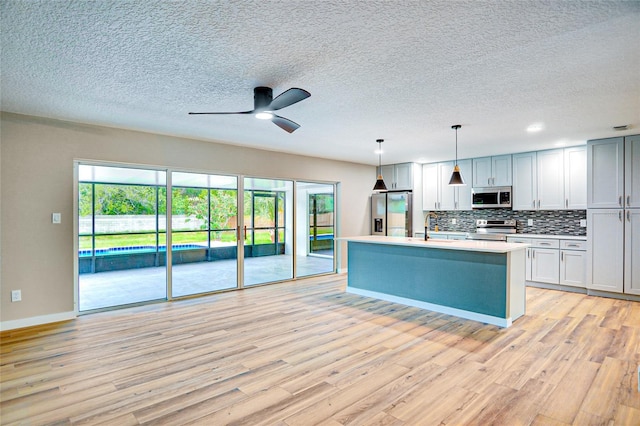 5938 Marlberry Dr, Orlando, FL 32819 - kitchen with stainless steel appliances, light wood-type flooring, light countertops, ceiling fan, and a textured ceiling