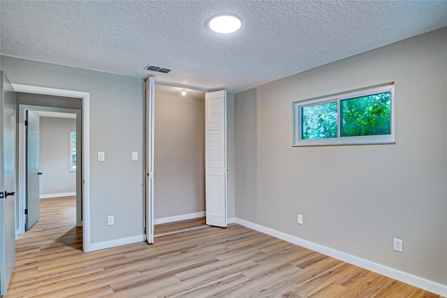5938 Marlberry Dr, Orlando, FL 32819 - unfurnished bedroom with light wood-style floors, a textured ceiling, and a closet