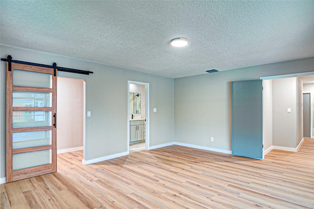 5938 Marlberry Dr, Orlando, FL 32819 - empty room with a barn door, light wood-type flooring, and a textured ceiling