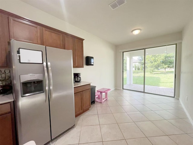 17504 Butterfly Pea Ct, Clermont, FL 34714 - kitchen featuring stainless steel refrigerator with ice dispenser, light tile patterned flooring, light countertops, and brown cabinets