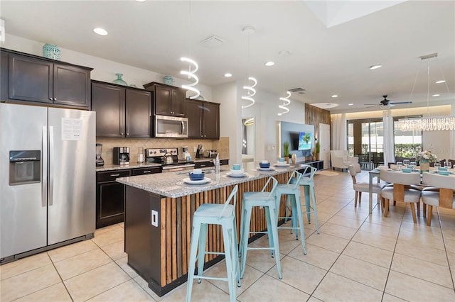 2108 Morocco Way, Kissimmee, FL 34747 - kitchen with stainless steel appliances, open floor plan, light stone countertops, light tile patterned floors, and backsplash
