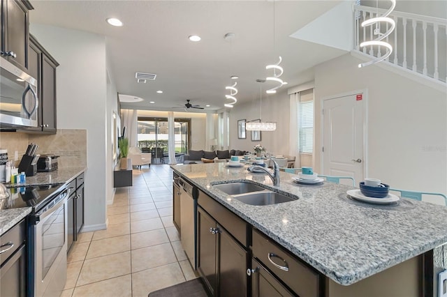 2108 Morocco Way, Kissimmee, FL 34747 - kitchen featuring appliances with stainless steel finishes, an island with sink, open floor plan, light tile patterned flooring, and tasteful backsplash