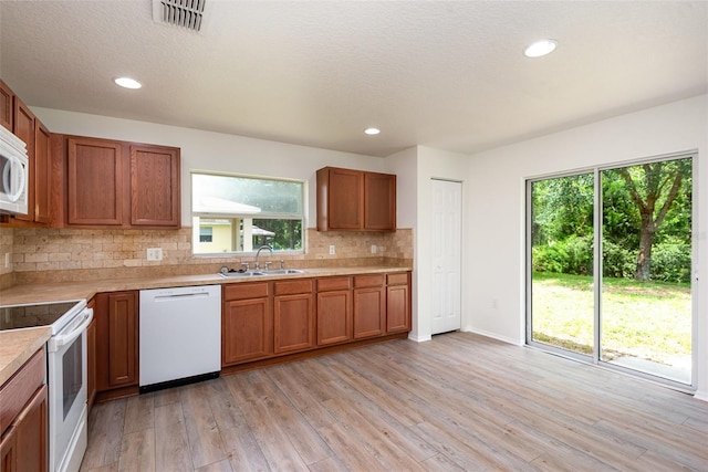 85 Levee Ln, Ormond Beach, FL 32174 - kitchen with white appliances, plenty of natural light, brown cabinetry, recessed lighting, and a textured ceiling