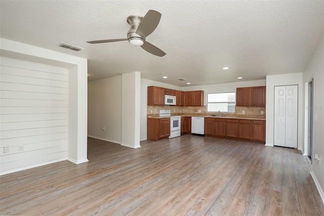85 Levee Ln, Ormond Beach, FL 32174 - kitchen featuring white appliances, light countertops, light wood-type flooring, tasteful backsplash, and brown cabinets