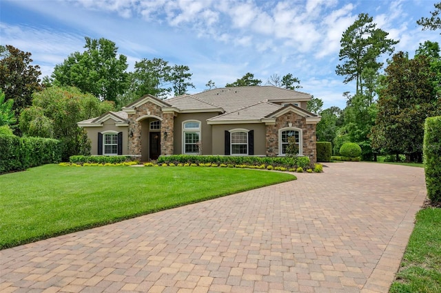 1462 Palm Bay Ct, Lake Mary, FL 32746 - mediterranean / spanish-style home with stone siding, stucco siding, curved driveway, and a front lawn