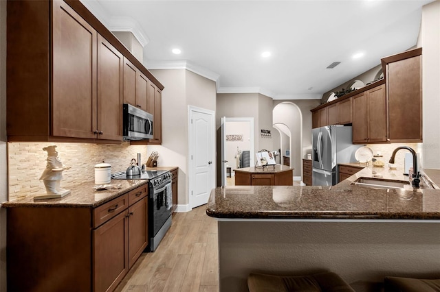 1462 Palm Bay Ct, Lake Mary, FL 32746 - kitchen with appliances with stainless steel finishes, ornamental molding, dark stone counters, arched walkways, and a kitchen island