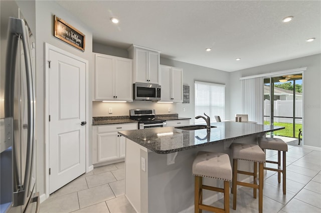 410 Winter Bliss Ln, Mount Dora, FL 32757 - kitchen with stainless steel appliances, a kitchen bar, light tile patterned floors, dark stone counters, and white cabinets